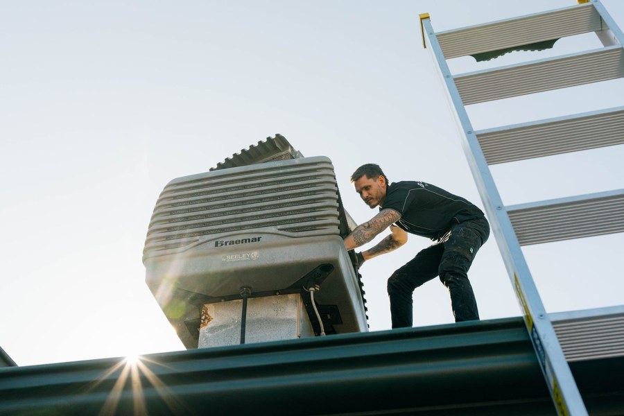 Two Belle Plumbing plumbers talking through an evaporative cooling job beside the van