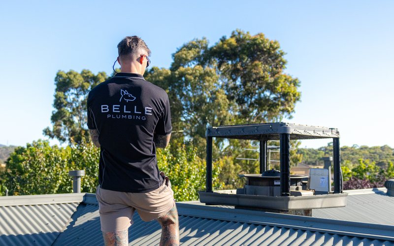 Belle Plumbing technician replacing a Braemar evaporative cooler on a roof